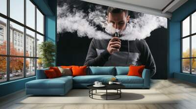 Young man vaping e-cigarette with smoke on black Wall mural