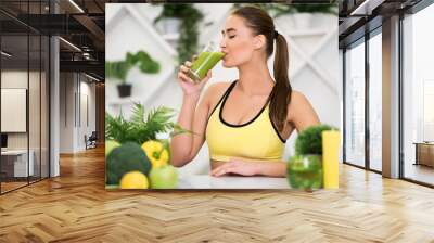 Young woman drinking fresh smoothie after home training Wall mural