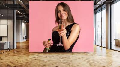 Young woman in evening dress holding champagne bottle and raising glass Wall mural