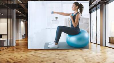 Young woman with gym ball and dumbbells at home, blank space Wall mural