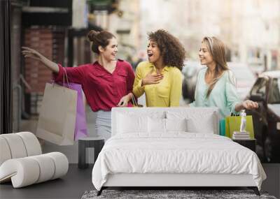 Young women walking with shopping bags on street Wall mural