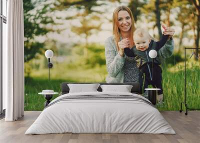 beautiful long-haired young mother in the summer sunshine park are sitting and playing with little cute sons Wall mural