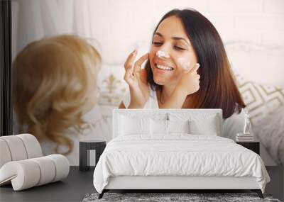 Beautiful woman with child. Woman in a white t-shirt. Mother with doughter using a cosmetics. Wall mural