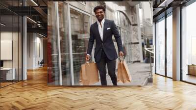 Black man in a city. Guy with shopping bags. Man in a black suit; Wall mural