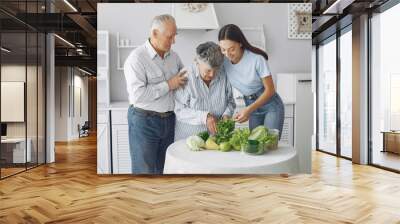 Family in a kitchen. Grandparents with granddaughter. Family made a salad Wall mural