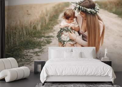 Family in a summer field. Mother in a wbrown dress. Cute little girl in a wreath Wall mural