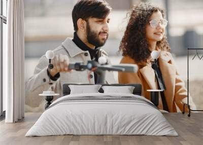 Interracial young couple with scooters in the city background Wall mural