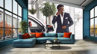 Man buying the car. Businessman in a car salon. Black male in a suit. Wall mural