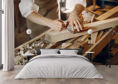 Man working with a wood. Carpenter in a white shirt Wall mural