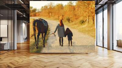 Mother and daughter next to horse. Little girl in a summer field. Family playing with a horse Wall mural