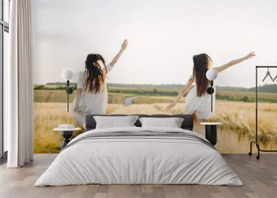 Portrait of two sisters in white dresses with long hair in a field Wall mural