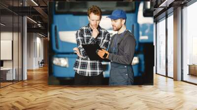 Two guys talking about work. Work in garage near truck. Transfer of documents with goods Wall mural