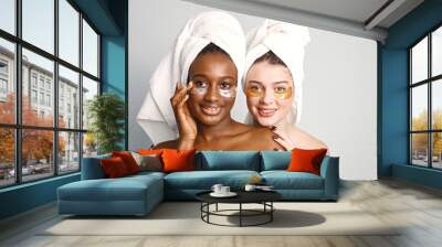 Two young teenage girls with eye patches on faces have a hair wrapped in towels Wall mural