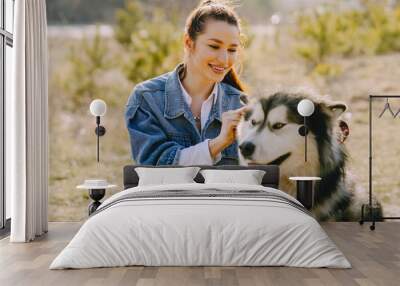 Woman in a spring forest. Girl with cute dog. Brunette in a jeans jacket. Wall mural