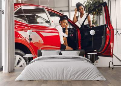 Women buying the car. Ladies in a car salon. Black girls near red car Wall mural