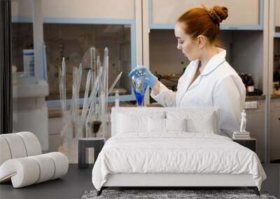 The girl in the lab mixing chemicals. The girl is holding a test tube with chemicals. Wall mural