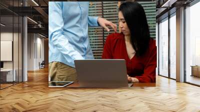 Boss touching shoulder of a young female employee in office at workplace. She is uncomfortable and afraid of sexual inappropriate abuse from a colleague. Concept of sexual harassment in the workplace Wall mural