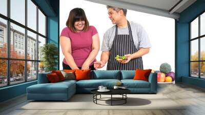 Happy overweight couple cooking a burger in the kitchen room. A vegetable on the table. Concept of happy family and binge eating Wall mural