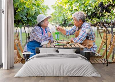 Portrait of senior winemaker holding in his hand a glass of new white wine. Smiling happy elderly couple enjoying a picnic together in own vineyard. Agricultural concept, Small business, retirement Wall mural