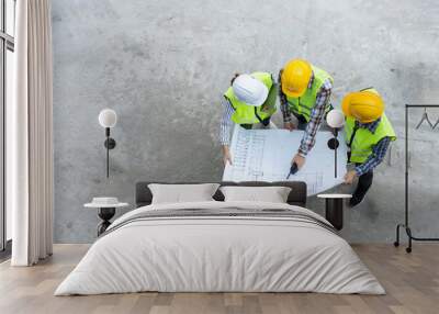 Top view of Asian engineer or Young Female Architect put on a helmet for safety and talk with a contractor on a construction building factory project, Concept of Teamwork, Leadership concept. Wall mural