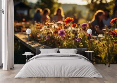 A group of friends gathered around a picnic setup in a blooming flower field, vibrant colors of natu Wall mural