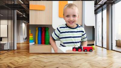 Child boy play with wooden train in kindergarten Wall mural