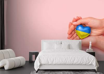 Hand holding a heart with Ukrainian national colors. Help Ukraine during the war Wall mural