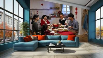 happy asian extended family laughing at the man’s joke while having reunion dinner on chinese new year’s eve in a cozy festive home interior Wall mural