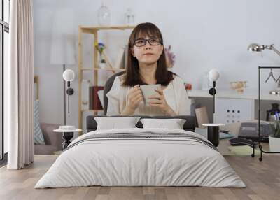 pensive asian japanese female chief editor taking brief rest from work and enjoying coffee while looking into distance. Wall mural