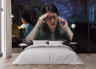 Selling products online concept. Portrait of angry frowning woman phone talking to annoyed clients for shipping problems at late night office. female coworker in back overtime working with parcel Wall mural