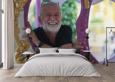 Caucasian Senior man with beard mustache has fun on carousel at the amusement park Wall mural