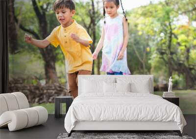 Group of multiracial children in line to jumping from stone chair to another one chair outdoors in summer park. Adorable kids have fun playing together in garden. Selective focus on little boy Wall mural