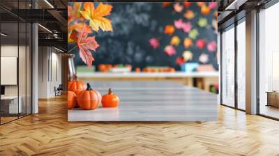 Decorative pumpkins and autumn leaves on a table with colorful fall-themed decorations in the background, perfect for seasonal settings. Wall mural