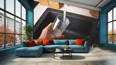 Filling glass of water from stainless steel kitchen faucet. Drinking water concept Wall mural