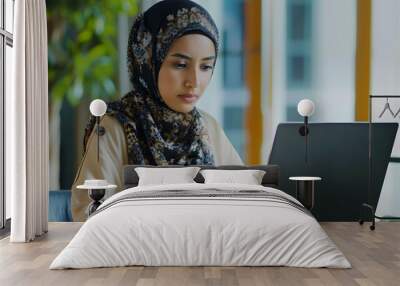 Young muslim woman wearing headscarf working on laptop in office  Wall mural