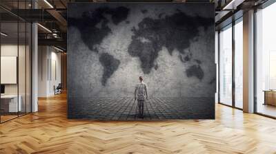 Person stands in front of a concrete wall looking at the world map. Travel limitations concept Wall mural