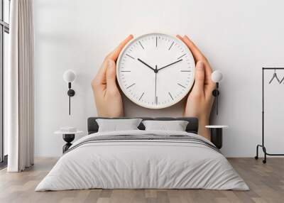 Close-up of hands holding a minimalistic round wall clock on white background, depicting time management and punctuality. Wall mural