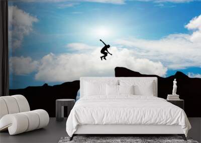 Man jump through the gap between hill.man jumping over cliff on sunset background,Business concept idea Wall mural