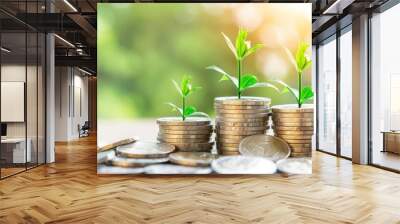 Stacked coins with sprouting plants symbolizing investment growth, financial success, and savings with green bokeh background. Wall mural