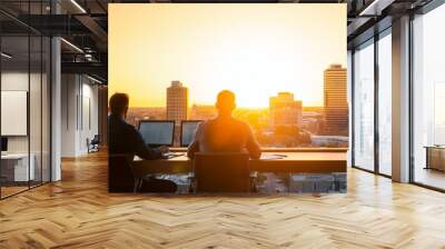 Two professionals work in an office with a stunning sunset view, symbolizing productivity and inspiration in a modern environment. Wall mural