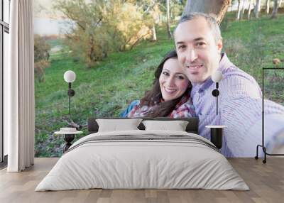 Portrait of happy couple taking a selfie in the park Wall mural