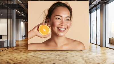 Beauty. Smiling woman with radiant face skin and orange portrait. Beautiful smiling asian girl model with natural makeup, healthy smile and glowing hydrated facial skin. Vitamin C cosmetics concept Wall mural