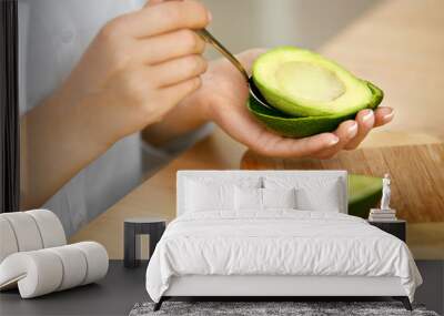 Eating Avocado. Woman Hands Peeling Fresh Avocado With Spoon Wall mural