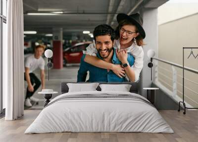 Friends Having Fun At Mall Parking. Woman Sitting On Man Back Wall mural