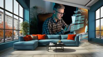 Man In Glasses And Plaid Shirt Analyzing Data On Digital Interface In Modern Office Setting, Representing Technology, Innovation, And Data Analysis. Concentrated Professional Working With High-Tech  Wall mural