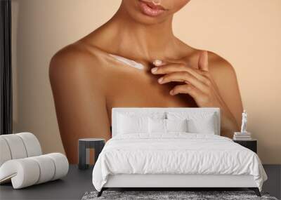 Skin care. Closeup woman's body with cosmetic cream on skin. Beautiful black girl with moisturizing lotion on hydrated body skin at studio Wall mural