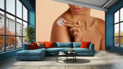 Skin care. Closeup woman's body with cosmetic cream on skin. Beautiful black girl with moisturizing lotion on hydrated body skin at studio Wall mural