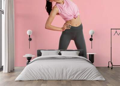 Stretch. Sport woman stretching body, warm up on pink background Wall mural