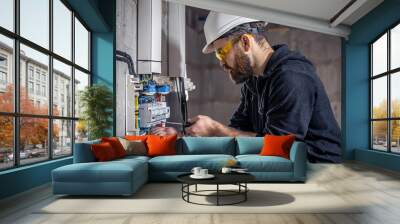 A male electrician works in a switchboard with an electrical connecting cable. Wall mural