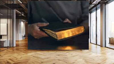 A man holds a Bible in his hands. Bible with golden pages. Wall mural